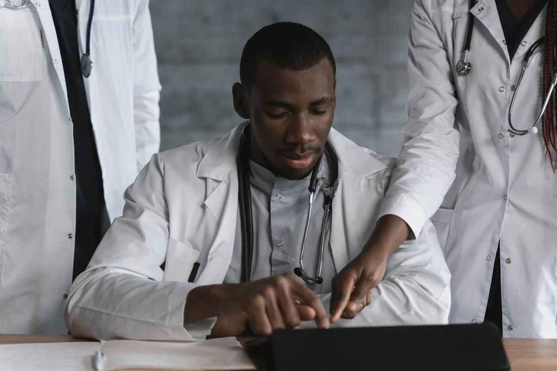 doctors_patient_discussion Team of medical professionals reviewing information together on a digital tablet in a clinical setting